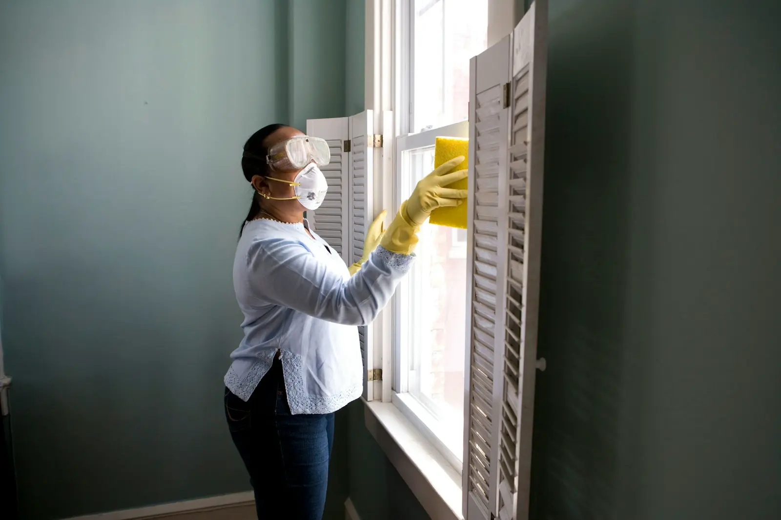 Cleaner wiping a bright window with professional protective equipment
